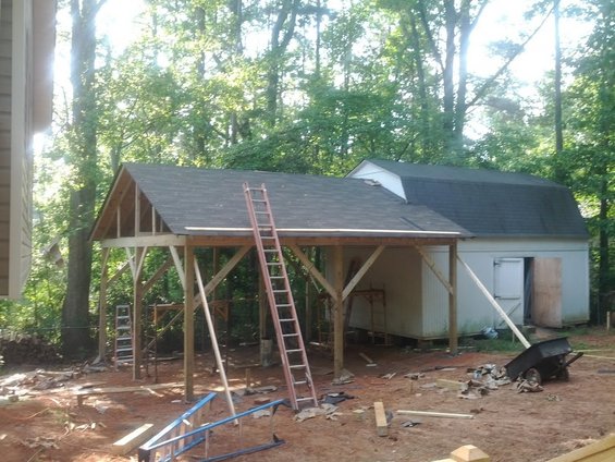 Construction site with unfinished carport, shed, and ladders