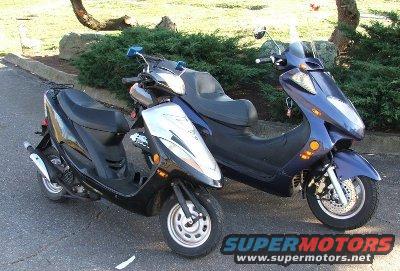 Two scooters parked on pavement, one black and silver, the other dark blue