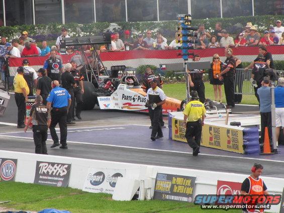 Drag racing scene with a dragster and crew members on the track