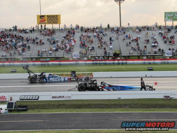 Two drag racing cars on a track, one blue with white and red stripes, the other blue and white with 'MATCO TOOLS' branding