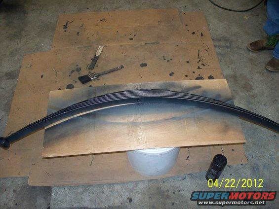 Black leaf spring on wooden board with paint brushes and spray can