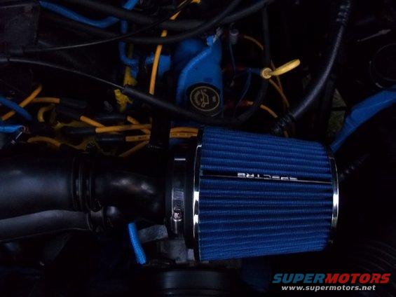 Blue Spectre cold air intake filter attached to black tubing in a dark engine bay