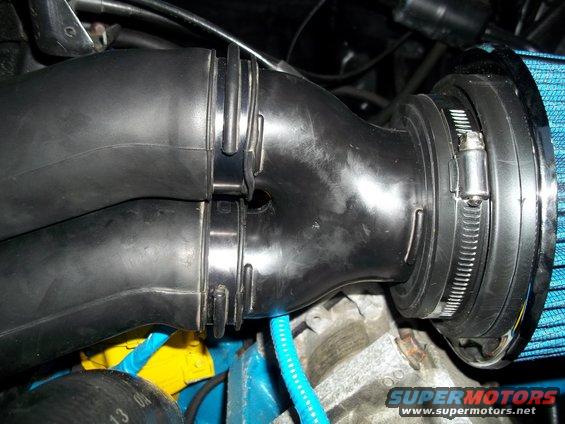 Close-up of a black plastic cold air intake tube with a blue air filter attached