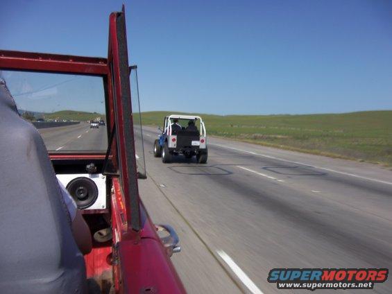 Two Jeeps driving on a highway, one blue and white, the other red
