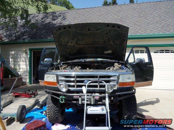 Front view of pickup truck with hood open, showing engine bay and aftermarket bumper