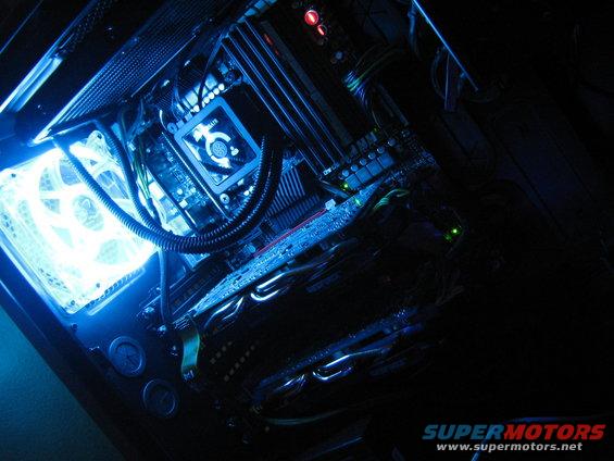 Computer internals with blue LED lighting, showing motherboard, fan, and graphics card