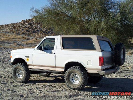1996 Ford Bronco parked on sand, spare tire mounted on rear door
