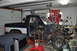 1986 Ford Bronco - A pickup truck is disassembled in a garage, with its engine compartment and front end completely removed.