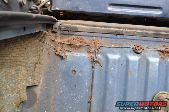 Rusted blue interior panel with visible dirt and insulation