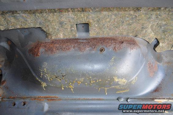Interior metal panel with rust and yellowing residue, under carpet padding
