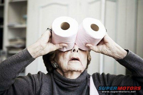 Woman holding toilet paper rolls to her eyes like binoculars