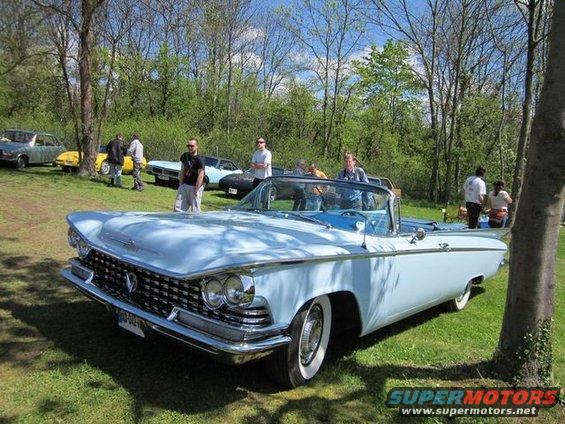 Light blue 1959 Buick convertible with a chrome grille and whitewall tires parked on grass