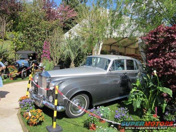 Gray and silver Rolls-Royce Silver Cloud parked on grass with flowers