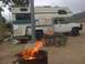 1997 Dodge 3500 - A white pickup truck with a camper shell is parked at a campsite with a fire pit in the foreground.