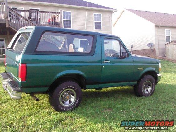 Green Ford Bronco parked on grass in front of a house
