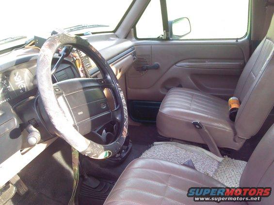 Brown leather seats and dashboard of a 1992 Ford Bronco, with a camouflage steering wheel cover