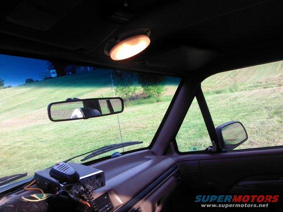 Interior view of a vehicle with a CB radio on the dashboard and a grassy field visible through the windshield