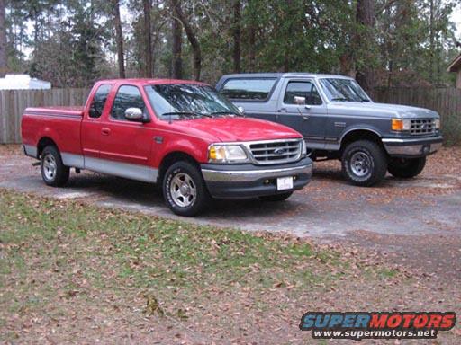 Red Ford F-150 pickup and a gray Ford Bronco parked outside