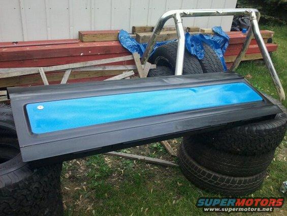 Black door panel with blue insert, resting on tires