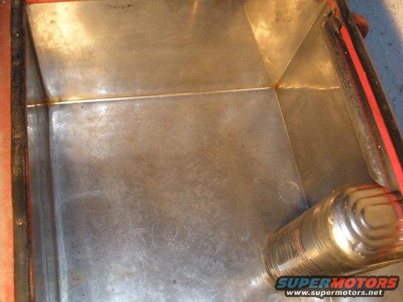 Inside of a metal Coca Cola cooler with a can on the side