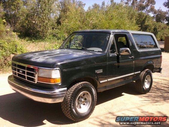 Dark green Ford Bronco with faded paint on the hood, parked outdoors