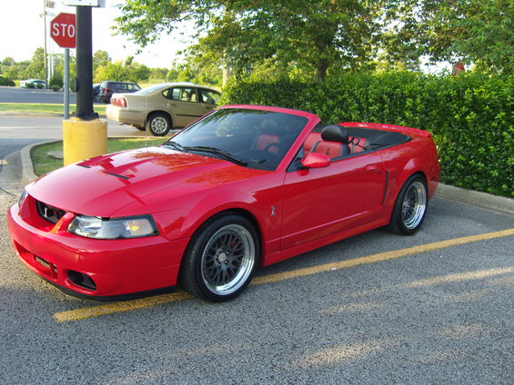 Red 2007 Ford Mustang convertible parked on asphalt with yellow line
