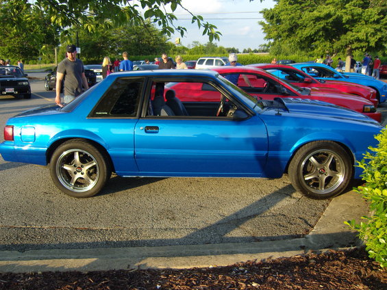 Blue coupe parked in a lot with other cars behind it