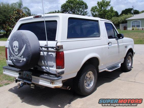 White 1995 Ford Bronco with pirate skull spare tire cover parked on pavement