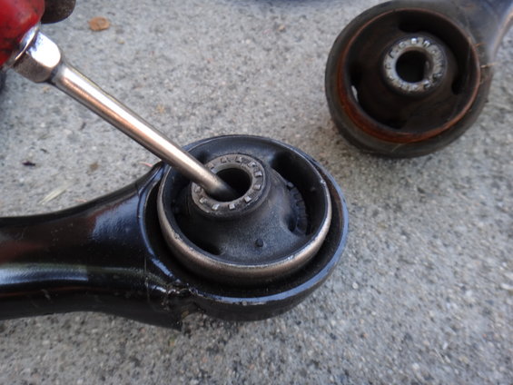 Close-up of a front lower control arm bushing with a tool inserted