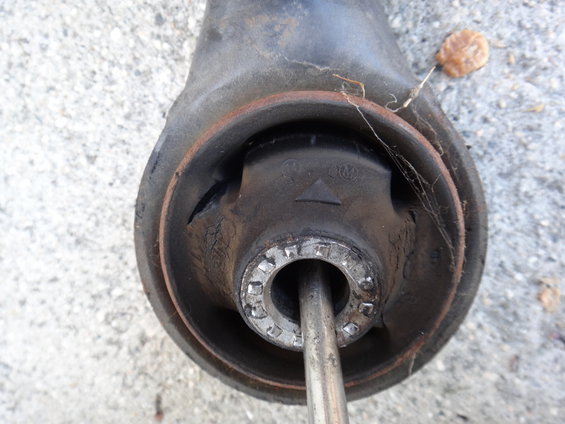 Close-up of a worn suspension part with a metal rod inserted. Rubber is cracked and rusted