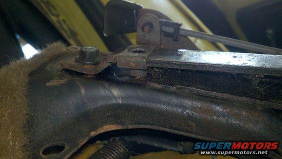 Close-up of a rusty seat adjustment mechanism with visible bolts and springs