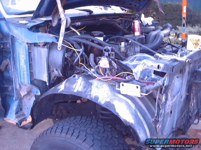 Engine bay and fender of a blue vehicle with body damage