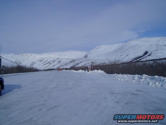 Snowy landscape with a truck parked on the side of a road