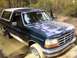 1992 Ford Bronco - A 1992 Ford Bronco is stuck in a muddy off-road trail with its tires deep in the mire.