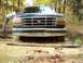 1992 Ford Bronco - A person attempts to push a 1992 Ford Bronco out of a muddy off-road trail.