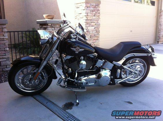 Black Harley-Davidson motorcycle parked in driveway. Chrome accents on wheels, engine, and exhaust