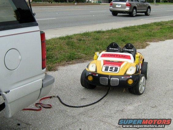 Yellow toy car with 'Pontiac' and '19' on it being towed by a larger vehicle
