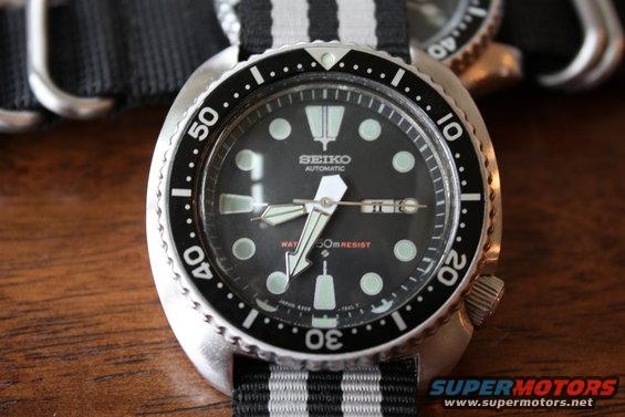 Close-up of a Seiko automatic dive watch with a black dial and striped NATO strap