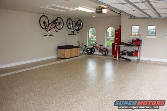 Garage interior with bicycles hanging on wall, workbench with tools, and two bicycles on the floor