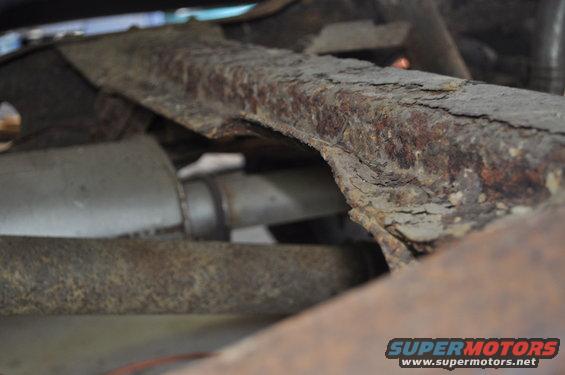 Heavily rusted frame rail and exhaust pipe visible