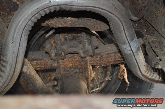 Rear axle assembly with leaf springs and dual exhaust pipes, heavily rusted