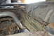 1986 Ford Bronco - Undercarriage view of a vehicle, focusing on the fuel tank and exhaust system, with visible rust and wear.