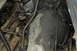 1986 Ford Bronco - Close-up view of greasy engine and transmission components, with visible wiring and metal linkages.