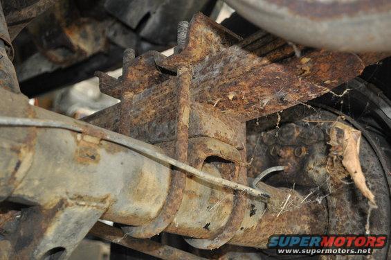 Heavily rusted rear axle and leaf spring assembly with U-bolts and brake line