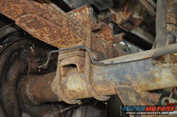 Close-up of rusty rear axle and leaf spring assembly on a vehicle