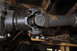 1986 Ford Bronco - Close-up view of a driveshaft universal joint, showing wear and grease. The Supermotors.net logo is visible in the lower right corner.