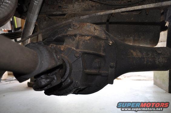 close-up of rusty rear axle and driveshaft on underside of vehicle