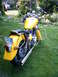 1976 Yamaha Virago - A yellow motorcycle is parked on a grassy lawn, showing its rear end and chrome exhaust pipes.