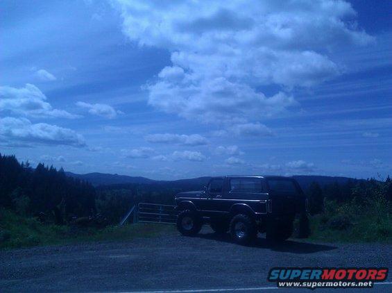 Black 1978 Ford Bronco parked on a gravel lot with a scenic mountain view
