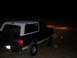 1992 Ford Bronco - A black and white Ford Bronco with a lifted suspension and roof lights is parked at night.